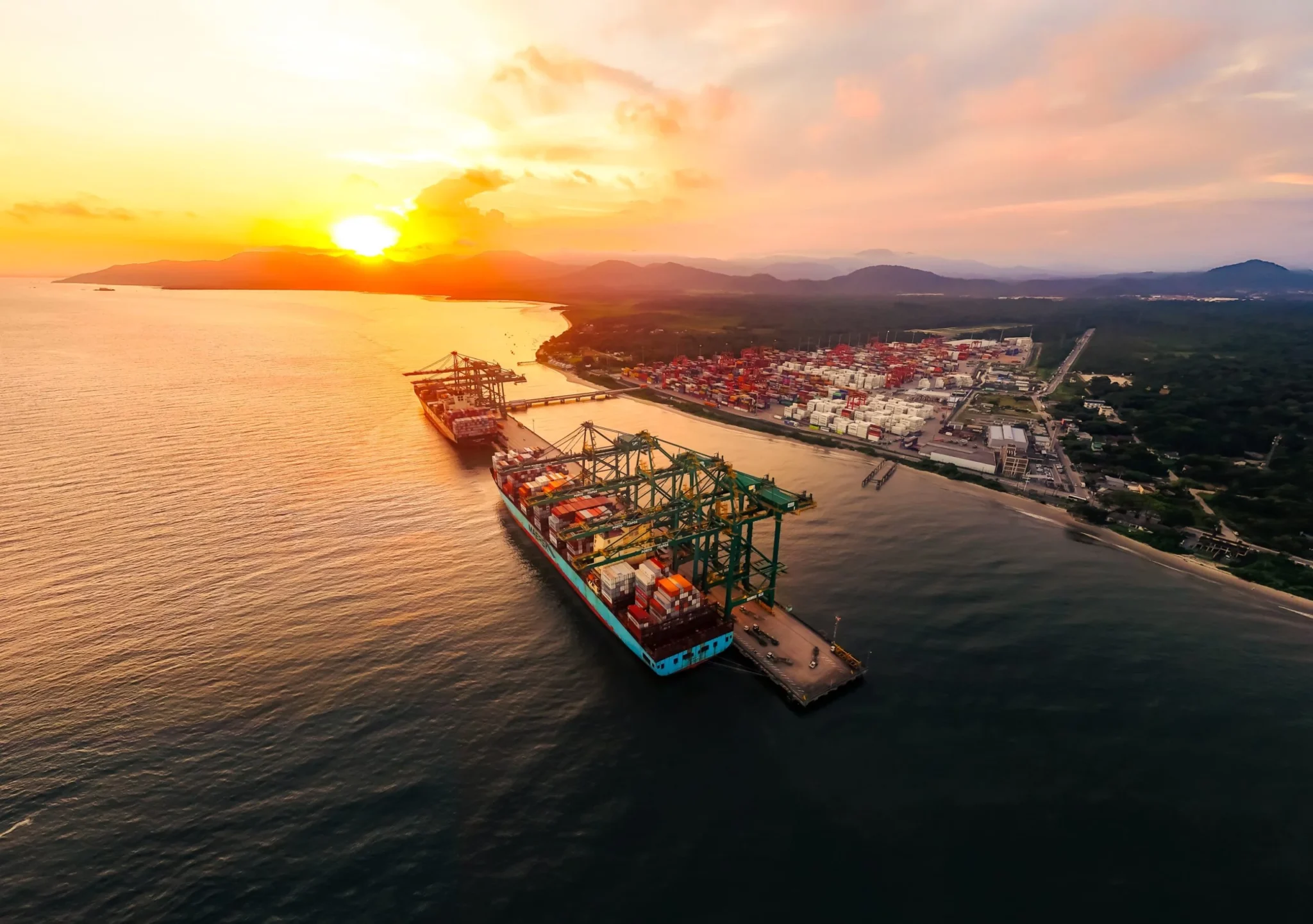 Vista a&eacute;rea do Porto Itapo&aacute; ao p&ocirc;r do sol, com navios porta-cont&ecirc;ineres atracados